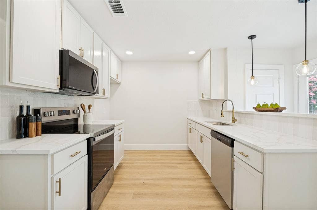109 Shadow Drive, Red Oak, TX 75154 Galley kitchen featuring white cabinetry with gold-tone hardware, light wood-finish flooring, white countertops, and a white subway tile backsplash