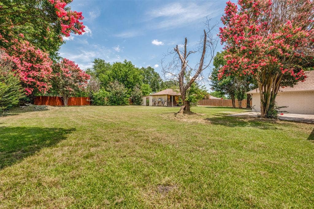 109 Shadow Drive, Red Oak, TX 75154 Spacious backyard featuring manicured lawn, mature trees, and a wooden privacy fence