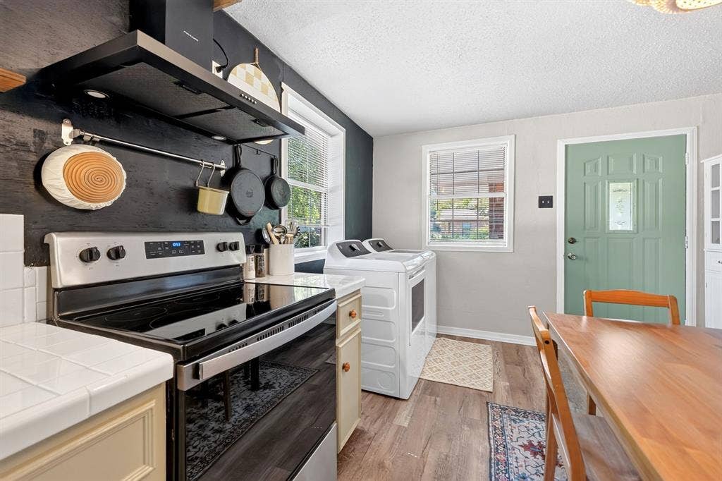 810 Edna Street, Athens, TX 75751 Kitchen featuring a black stainless steel range with a coordinating range hood, white tile countertops, and wood-finish flooring