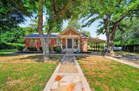 810 Edna Street, Athens, TX 75751 Brick exterior featuring a covered front porch, a stone and concrete walkway, mature trees, and a multi-vehicle carport