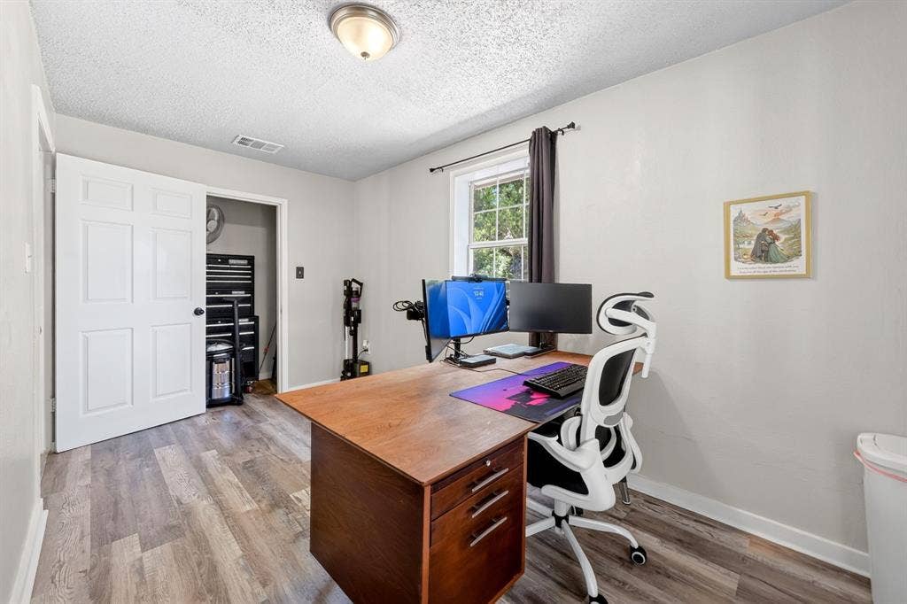 810 Edna Street, Athens, TX 75751 Light-filled room featuring wood-finish flooring, a window with dark drapery, a ceiling-mounted light fixture, and a closet with a paneled door