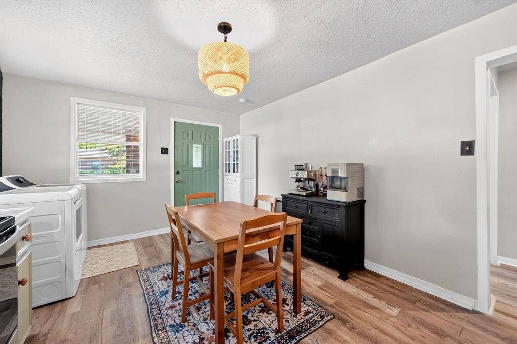 810 Edna Street, Athens, TX 75751 Dining area featuring wood-finish flooring, a decorative pendant light fixture, and a light green entry door with a window