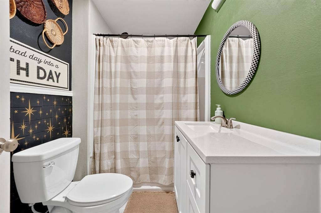 810 Edna Street, Athens, TX 75751 Bathroom featuring a white single-basin vanity with integrated countertop, a circular mirror, and a commode