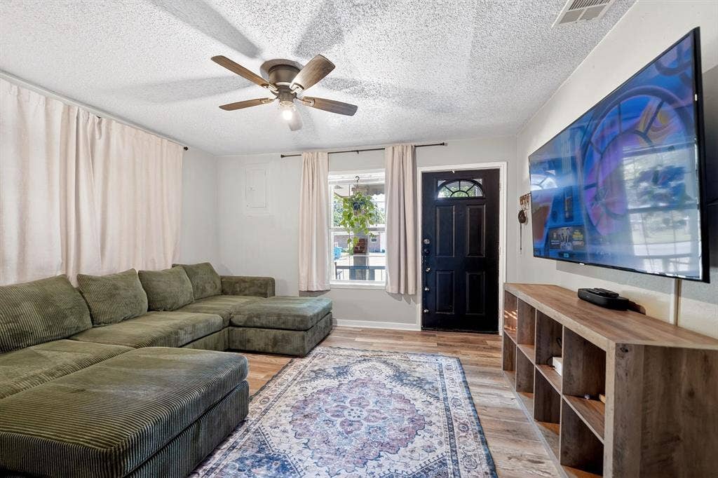 810 Edna Street, Athens, TX 75751 Living area featuring wood-finish flooring, a ceiling fan with integrated lighting, and multiple windows with curtain rods