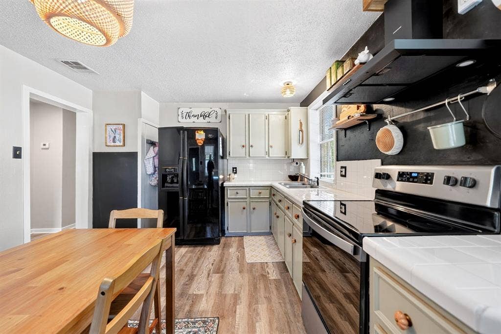810 Edna Street, Athens, TX 75751 Kitchen featuring wood-finish flooring, white tile countertops, subway tile backsplash, and light-toned cabinetry