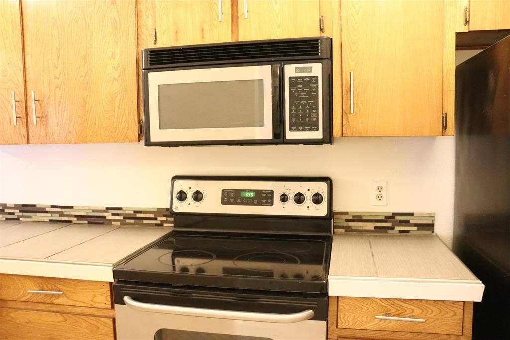 10020 Redondo Drive, Dallas, TX 75218 Kitchen with light wood-finish cabinetry and a mosaic tile backsplash