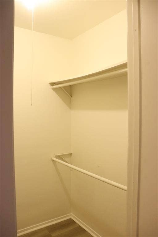 10020 Redondo Drive, Dallas, TX 75218 Walk-in closet with overhead shelf, clothing rod, and wood-finish flooring