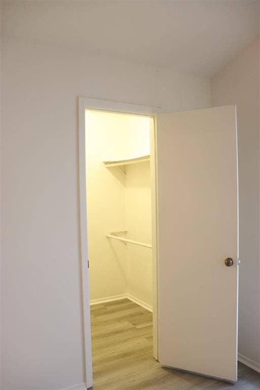 10020 Redondo Drive, Dallas, TX 75218 Interior closet featuring wood-finish flooring, white walls, and built-in shelving with a hanging rod
