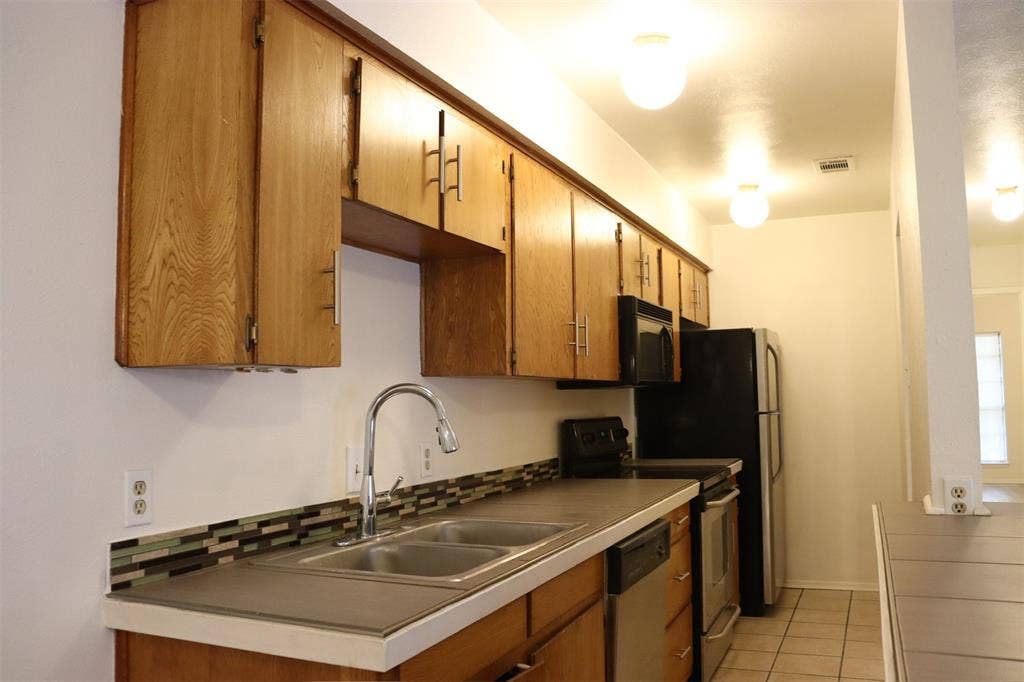 10020 Redondo Drive, Dallas, TX 75218 Kitchen featuring wood cabinetry, dual basin stainless steel sink with a gooseneck faucet, mosaic tile backsplash, and tile flooring