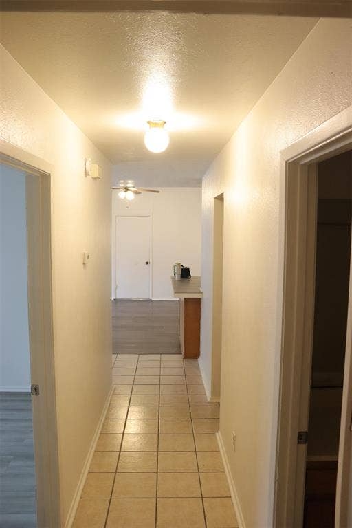 10020 Redondo Drive, Dallas, TX 75218 Hallway featuring tile flooring, neutral wall tones, and recessed lighting leading to an open living area with wood-finish flooring and a ceiling fan