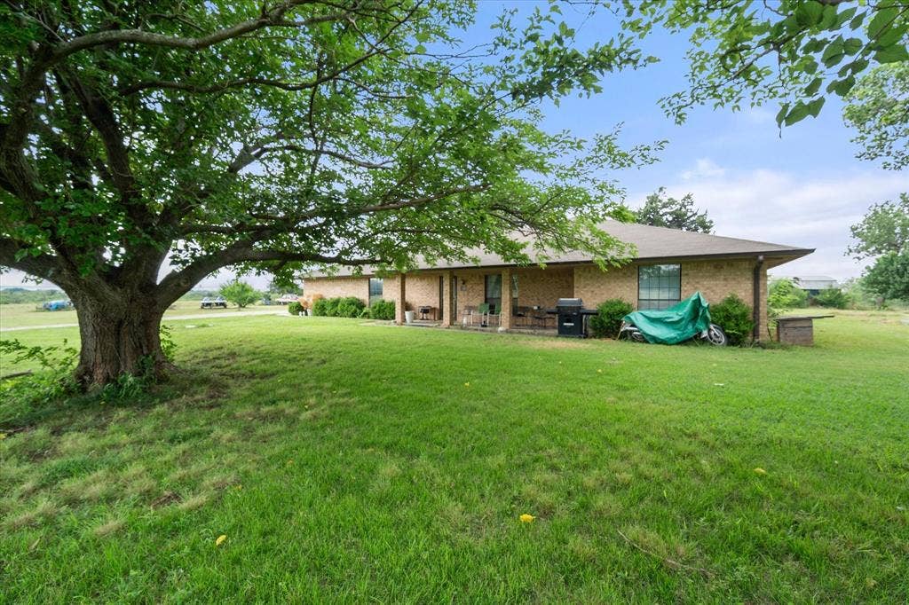 Mature trees and covered front porch make country life near the city still possible.