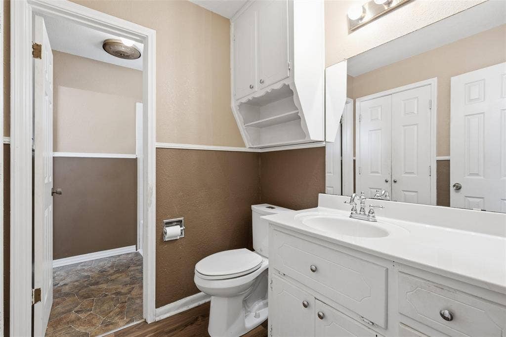 Bathroom featuring a single vanity with an integrated sink, chrome faucet, and a large wall-mounted mirror