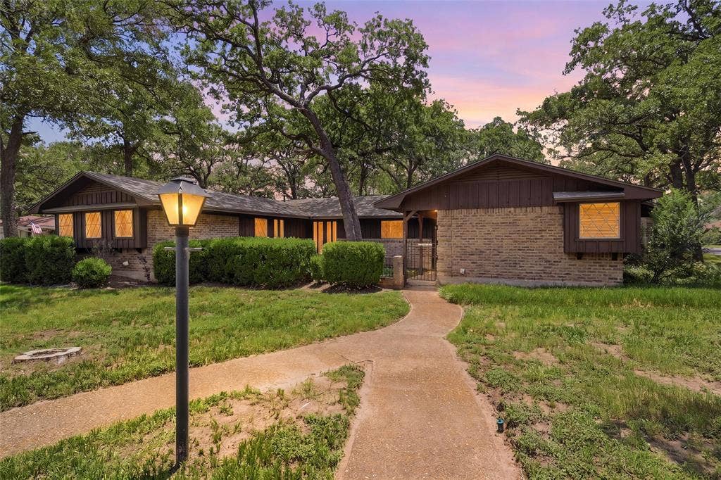 Mid-century modern residence featuring a brick facade, dark wood siding, and mature trees
