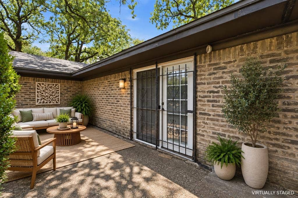 Private outdoor patio with brick exterior and mature tree canopy