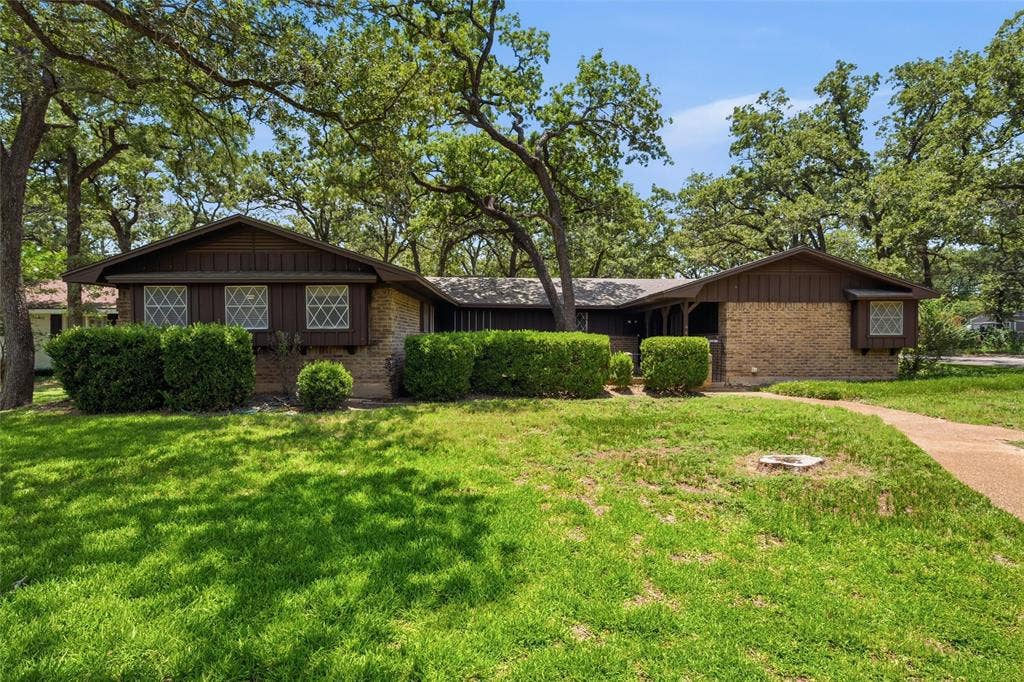 Ranch-style residence featuring a brick and dark wood exterior
