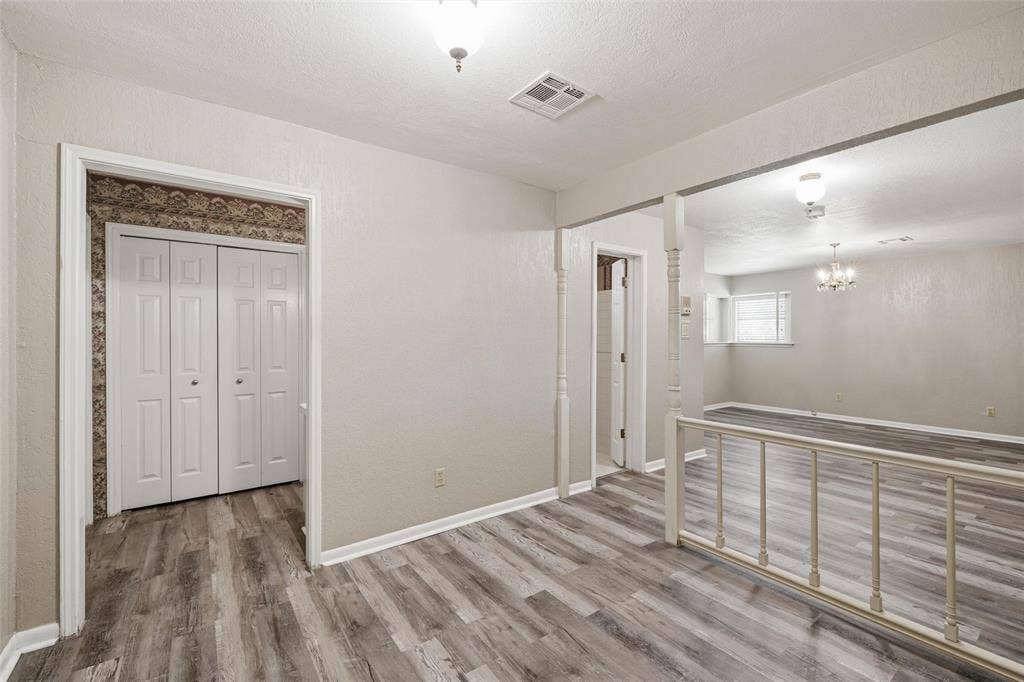 Interior hallway featuring wood-finish flooring, bi-fold closet doors, and neutral wall tones
