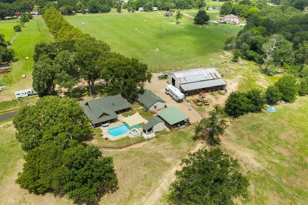 13494 County Road 2919, Eustace, TX 75124 Expansive property featuring a main residence with a swimming pool, detached covered patio, a large barn, and surrounding green acreage