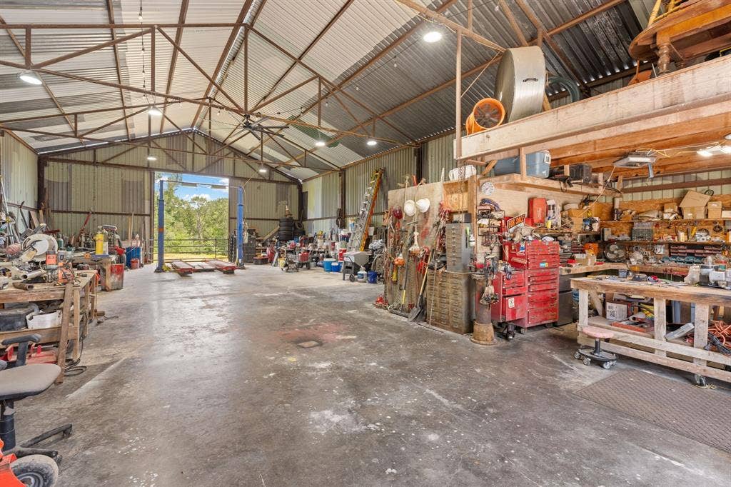 13494 County Road 2919, Eustace, TX 75124 Spacious metal-sided workshop featuring a concrete floor, high-bay lighting, open rafter ceiling, and a vehicle lift