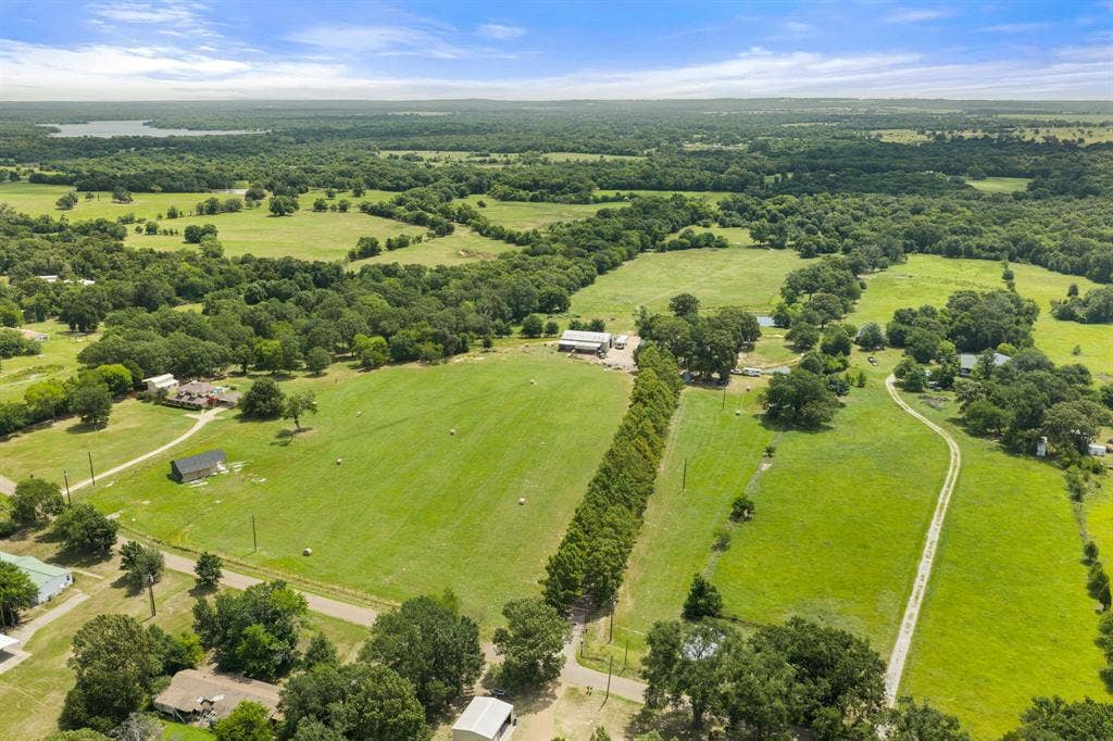 13494 County Road 2919, Eustace, TX 75124 Expansive rural landscape featuring lush green fields, scattered mature trees, and a distant body of water