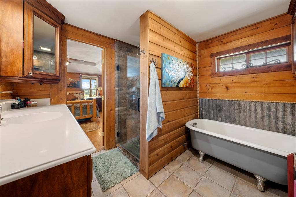 13494 County Road 2919, Eustace, TX 75124 Bathroom featuring a white vanity with integrated sink, wood-finish cabinetry, a glass-enclosed shower, a clawfoot bathtub, and tile flooring