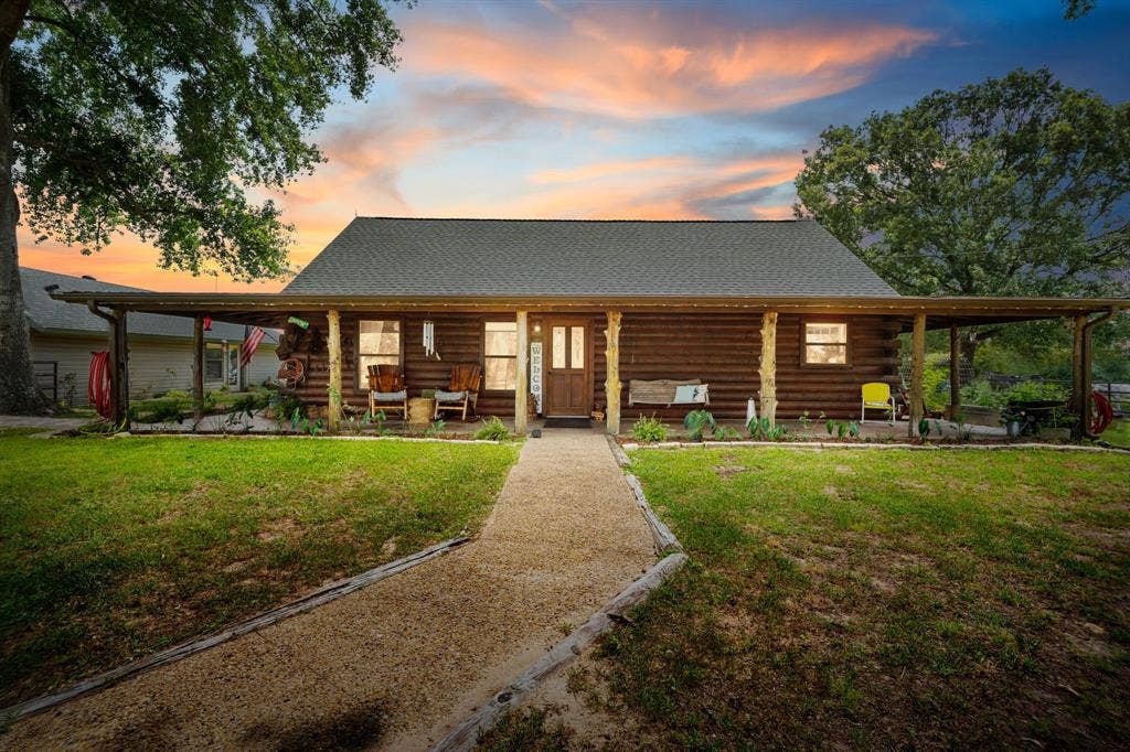13494 County Road 2919, Eustace, TX 75124 Log cabin exterior featuring a covered front porch, gravel pathway, and mature trees
