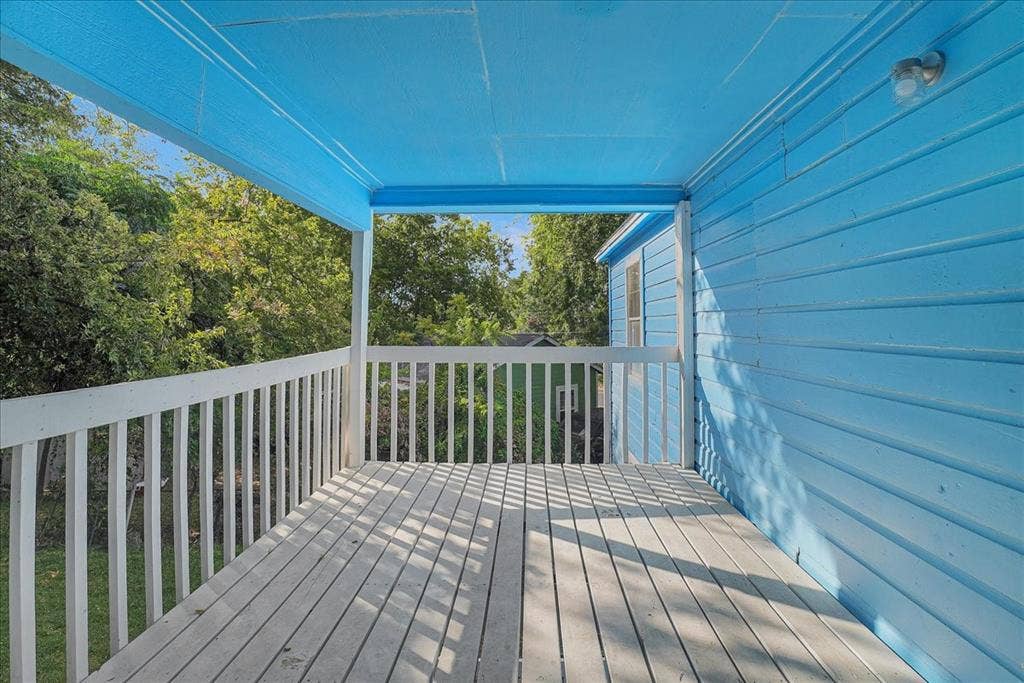 Covered porch featuring wood decking, wood railing, and plank siding