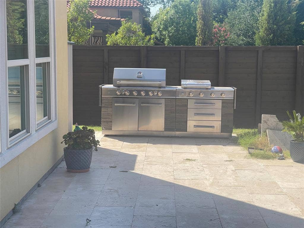 12226 Lazio Lane, Frisco, TX 75035 Outdoor kitchen featuring a built-in stainless steel grill, integrated storage, and a stone-look base