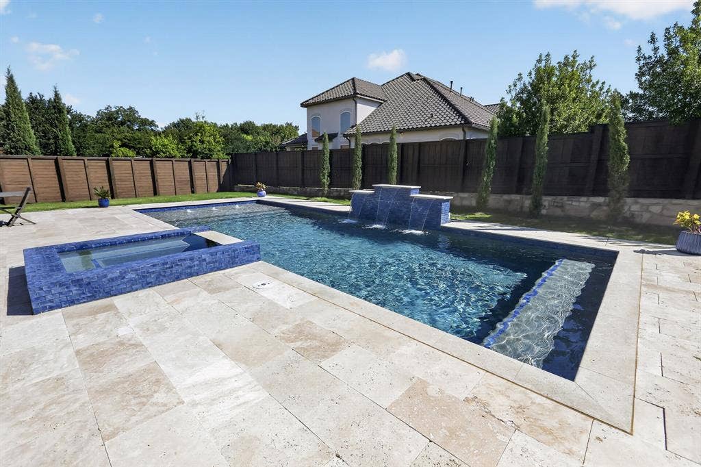 12226 Lazio Lane, Frisco, TX 75035 Contemporary swimming pool with integrated spa, featuring blue mosaic tile accents and a waterfall element