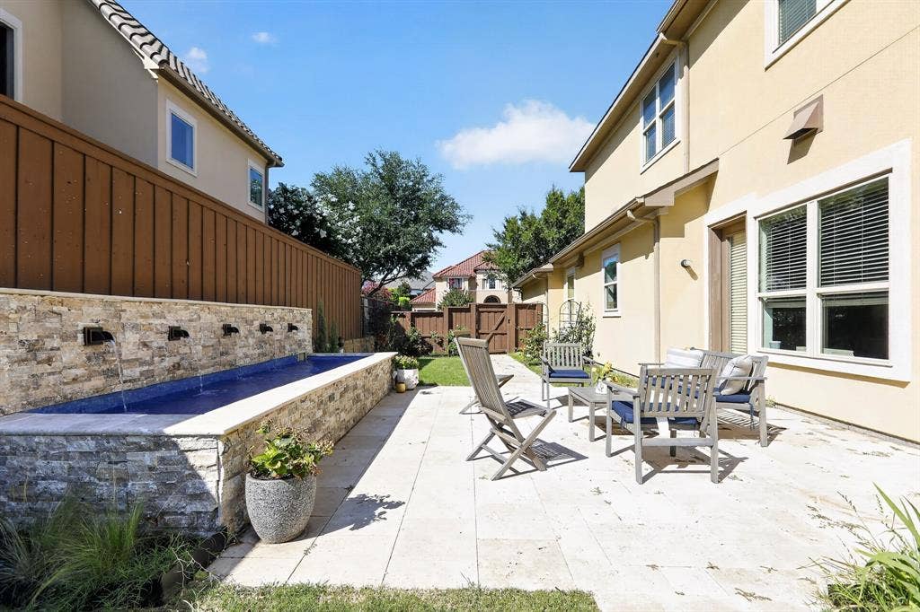 12226 Lazio Lane, Frisco, TX 75035 Exterior patio featuring a stone-clad water feature, stucco siding, a wood fence, and a grass lawn
