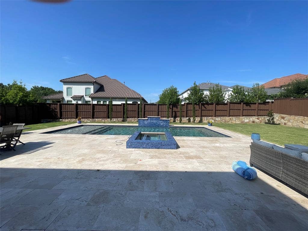 12226 Lazio Lane, Frisco, TX 75035 Expansive outdoor living area featuring a rectangular pool with a raised spa, surrounded by large format paver patio and green lawn