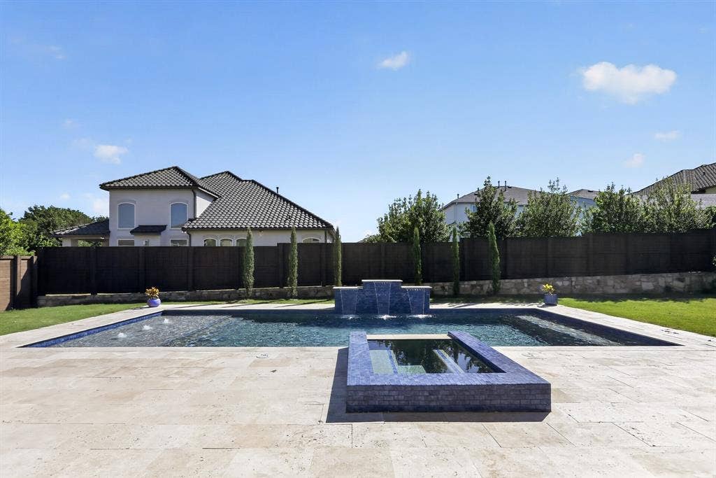 12226 Lazio Lane, Frisco, TX 75035 Outdoor living space featuring a rectangular swimming pool with integrated spa and water features, surrounded by a light-toned stone patio