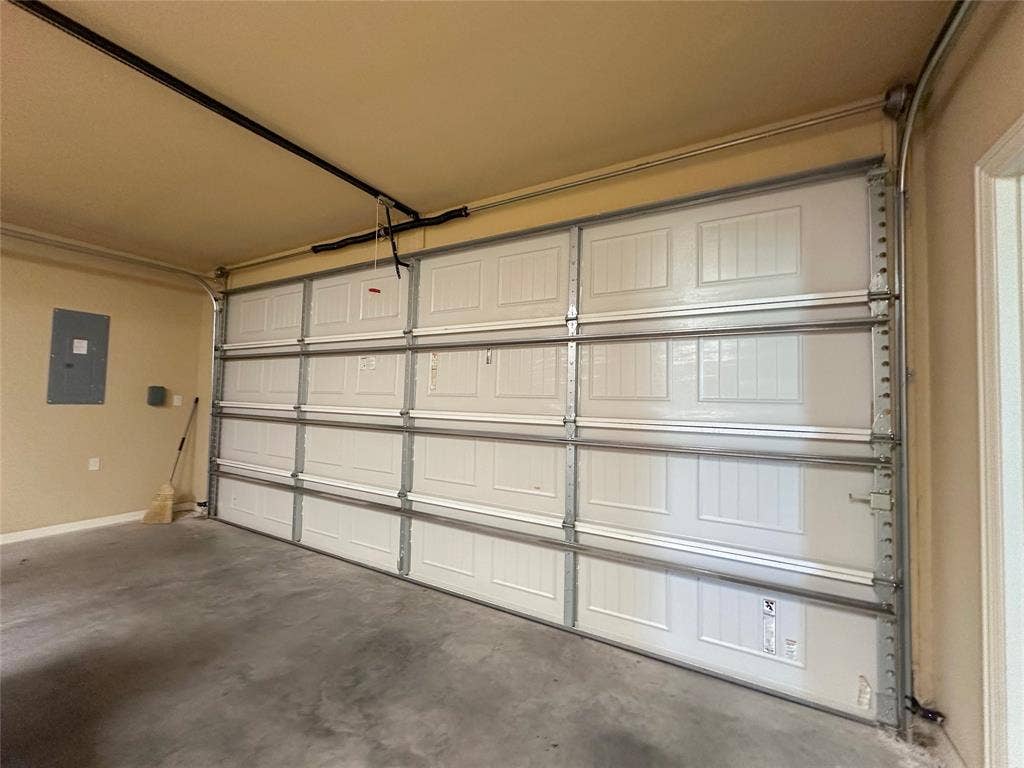 1100 Wessex Drive, Woodway, TX 76712 Spacious garage featuring a white paneled door, exposed metal track system, and concrete flooring