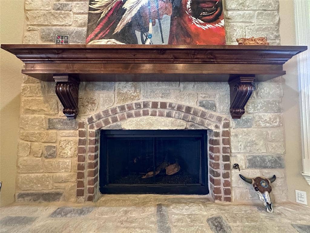 1100 Wessex Drive, Woodway, TX 76712 Stone fireplace featuring a brick arched firebox, substantial wood mantel with carved corbels, and a stone hearth