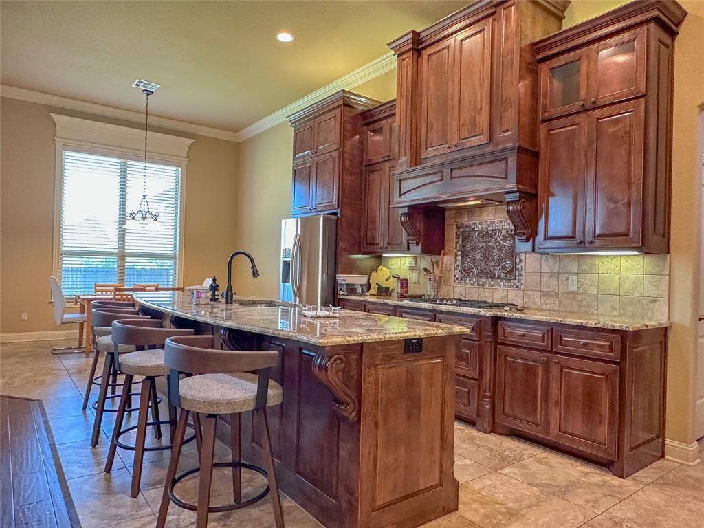 1100 Wessex Drive, Woodway, TX 76712 Kitchen featuring rich wood cabinetry, granite countertops, stainless steel appliances, and a tile backsplash with decorative inset
