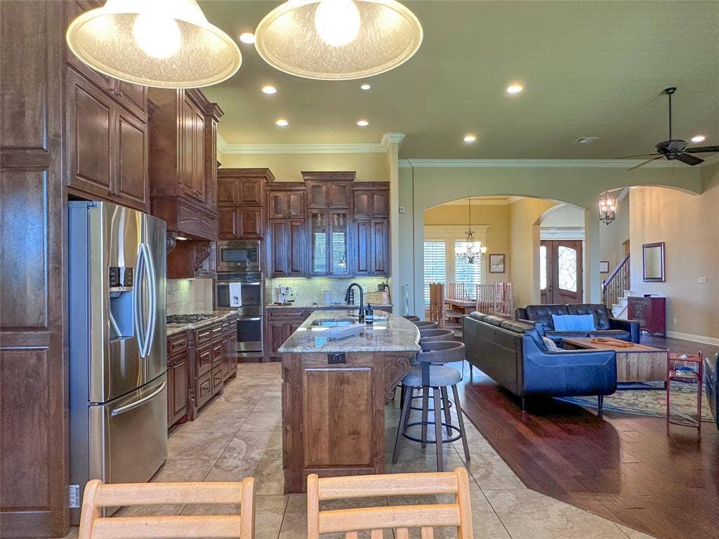 1100 Wessex Drive, Woodway, TX 76712 Kitchen featuring dark wood cabinetry, stainless steel appliances, a center island with a granite countertop, and recessed lighting