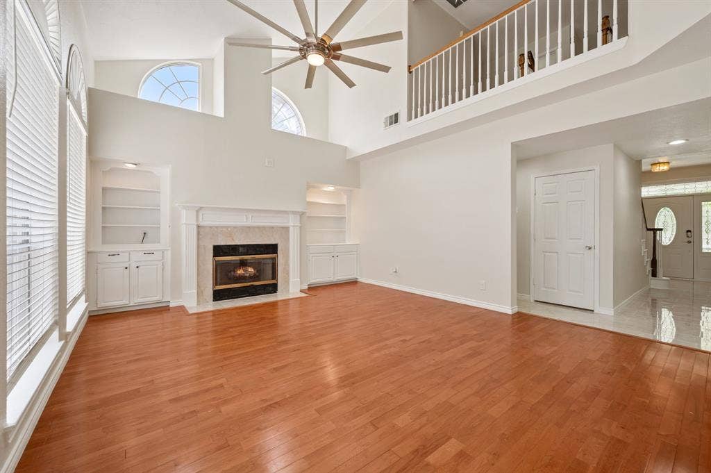 669 Water Oak Drive, Plano, TX 75025 Vaulted great room with wood-finish flooring, a ceiling fan, and high arched windows