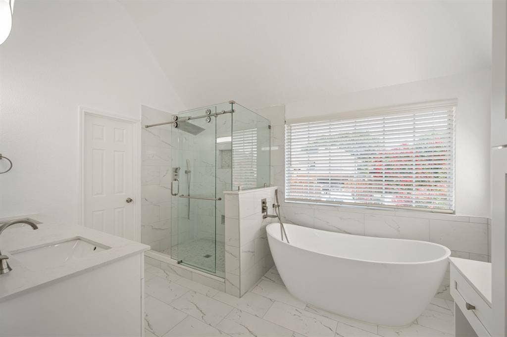 669 Water Oak Drive, Plano, TX 75025 Bathroom featuring a freestanding soaking tub, an enclosed glass shower, a single vanity with an undermount sink, a white countertop, and white tile flooring
