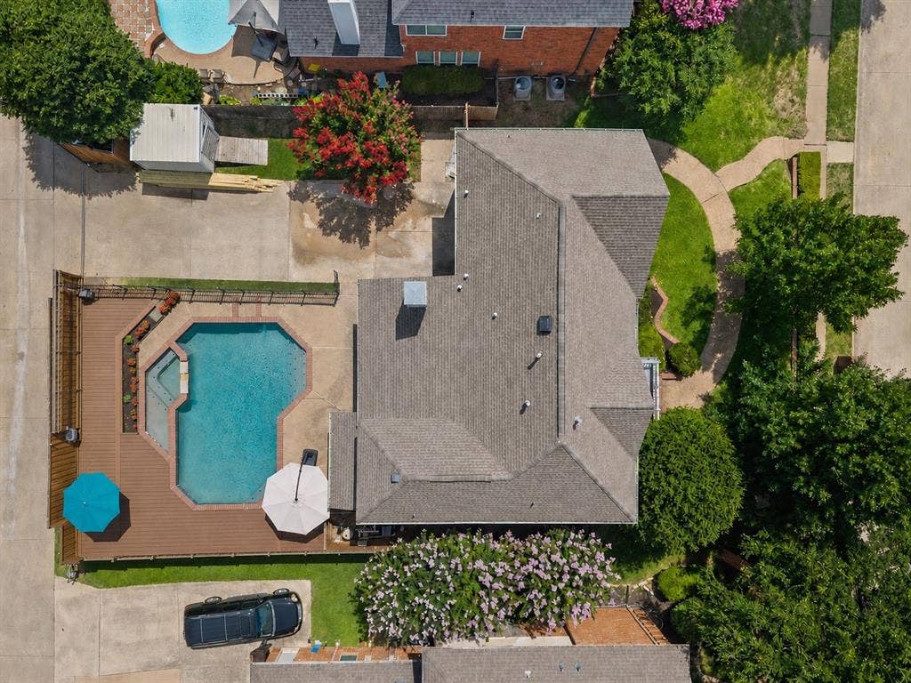 669 Water Oak Drive, Plano, TX 75025 Expansive backyard featuring a geometric swimming pool, surrounding wood-finish decking, and concrete patio