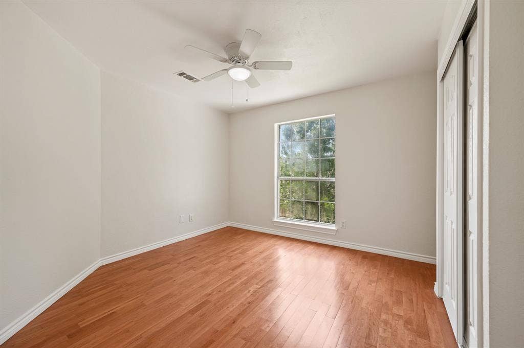 669 Water Oak Drive, Plano, TX 75025 Spacious room featuring wood-finish flooring, a large window, a ceiling fan with integrated lighting, and a closet with bi-fold doors