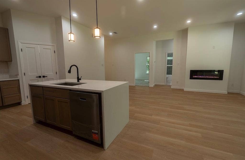 3315 Kyser, Dallas, TX 75216 Open-concept living area featuring a kitchen island with integrated sink and dishwasher, white quartz countertops, and pendant lighting