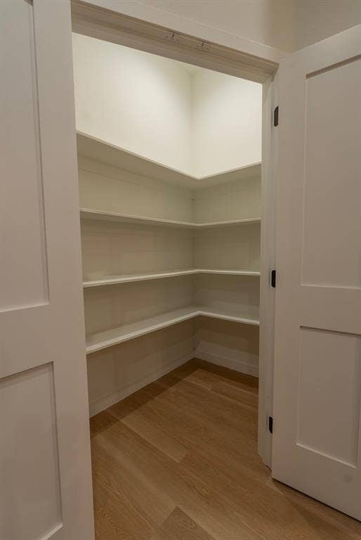 3315 Kyser, Dallas, TX 75216 Walk-in pantry featuring light wood-finish flooring, white built-in shelving, white walls, and a recessed ceiling light