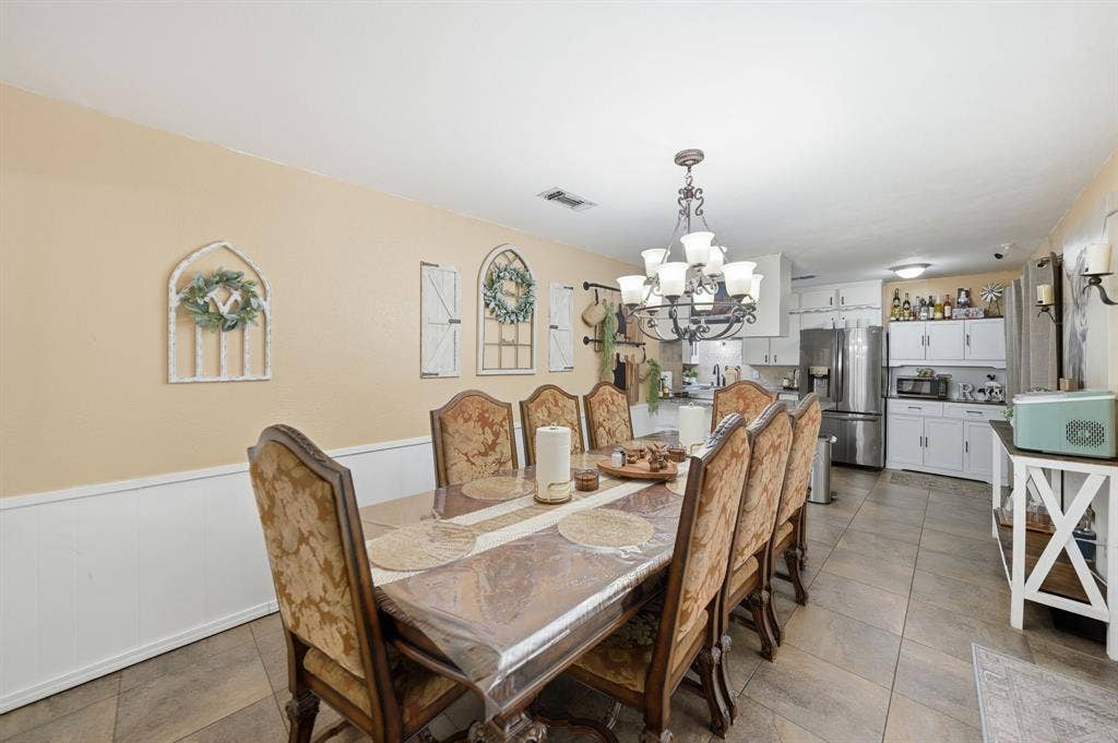 520 Thompson Drive, Saginaw, TX 76179 Dining area featuring a decorative chandelier, wainscoting, and tile flooring