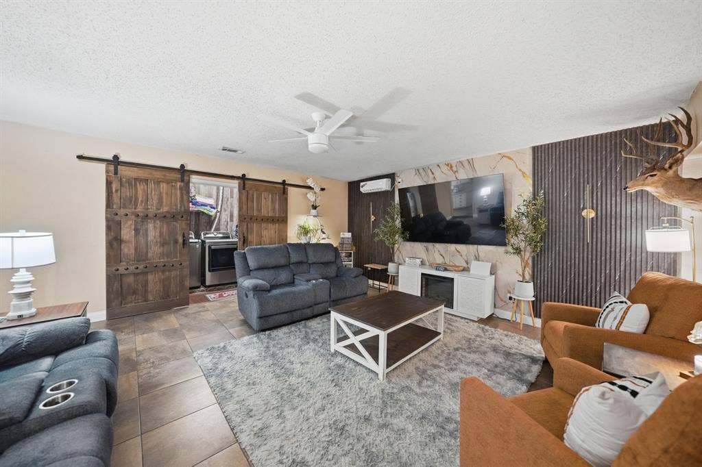 520 Thompson Drive, Saginaw, TX 76179 Living area featuring tile flooring, a ceiling fan, and a decorative accent wall with vertical paneling