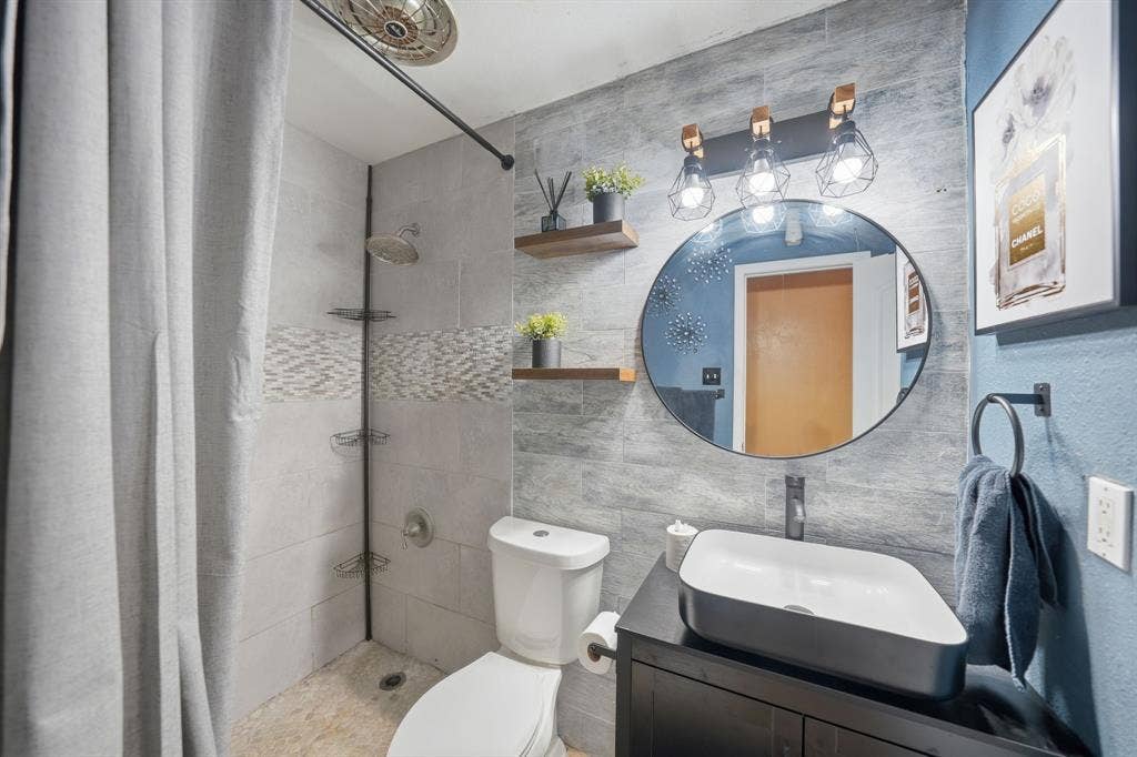 520 Thompson Drive, Saginaw, TX 76179 Bathroom featuring a vessel sink with a black vanity, round mirror, and industrial-style lighting