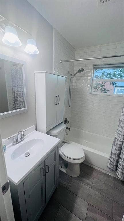 909 Laguna Drive, Denton, TX 76209 Bathroom featuring a white vanity with integrated sink, wood-finish flooring, a full bathtub with shower, and a built-in storage cabinet