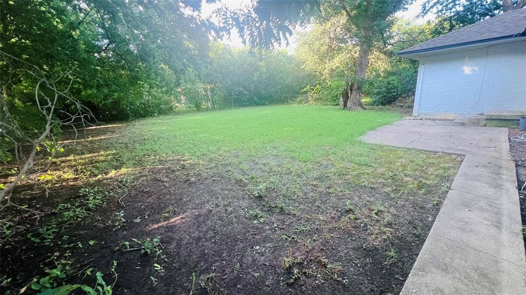 909 Laguna Drive, Denton, TX 76209 Expansive backyard featuring a partial lawn, mature perimeter trees, and a concrete patio