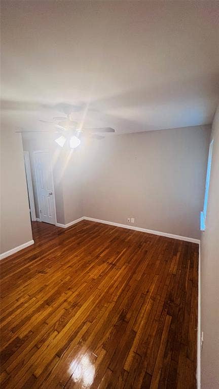 909 Laguna Drive, Denton, TX 76209 Room featuring rich wood-finish flooring, light gray walls, white baseboards, a ceiling fan with integrated lighting, and a white interior door