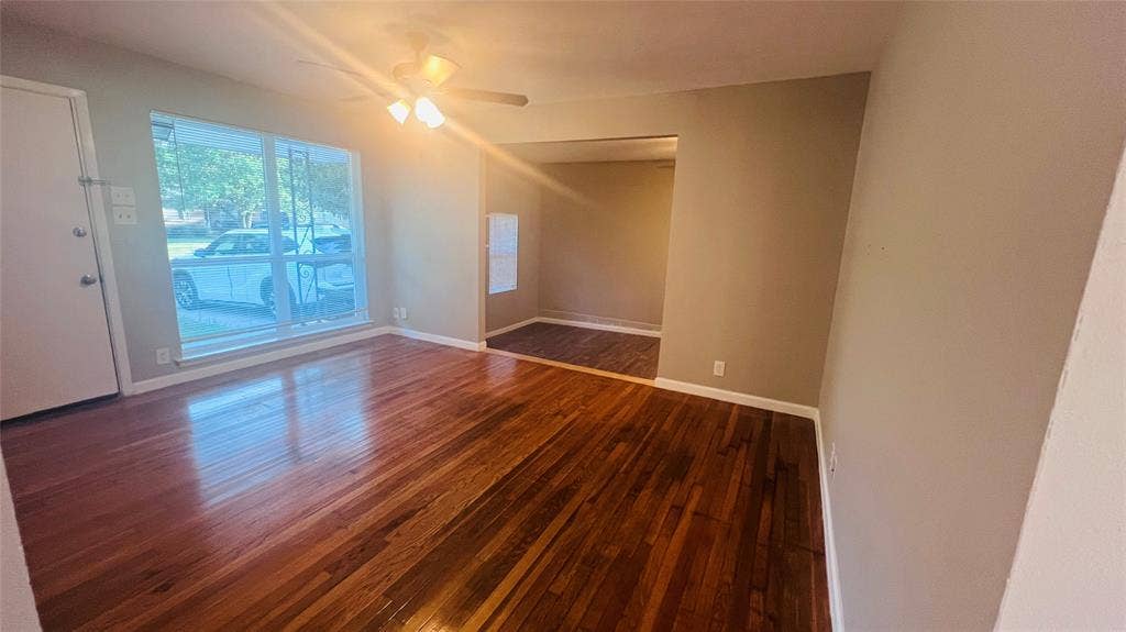 909 Laguna Drive, Denton, TX 76209 Spacious room featuring wood-finish flooring, a large window, a ceiling fan with integrated lighting, and neutral wall tones