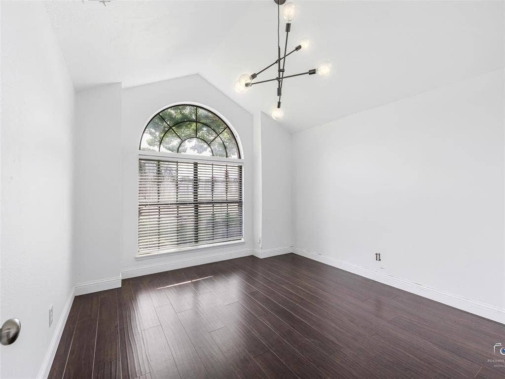 6701 Vero Drive, Plano, TX 75023 Bedroom three features a vaulted ceiling with an arch-top window, the same wood flooring, and a modern sputnik-style chandelier