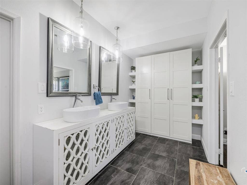 6701 Vero Drive, Plano, TX 75023 Bathroom featuring a dual vanity with vessel sinks, ornate cabinet fronts, pendant lighting, and a built-in storage unit with open shelving